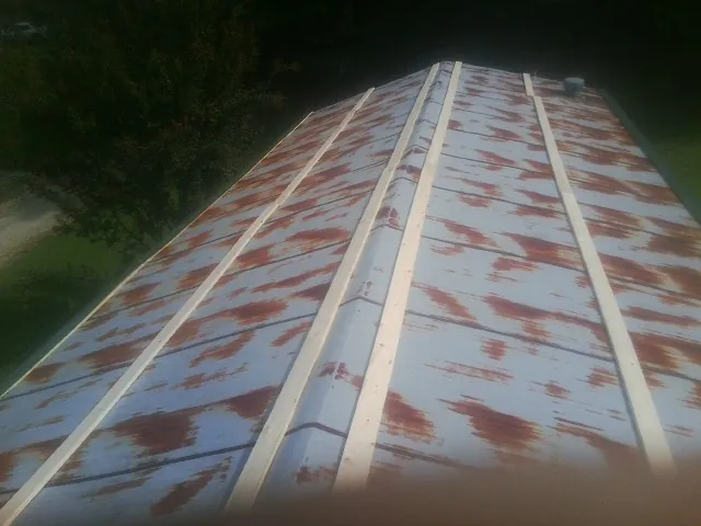 Rusted metal roof panels with new wood purlins before replacement in Trenton